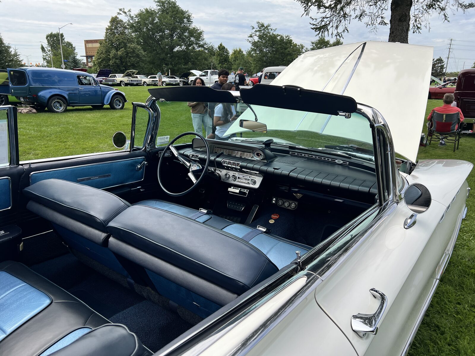 The blue and white interior of the 1960 Buick convertible, showing the bench seats, the chrome dashboard and the steering wheel.