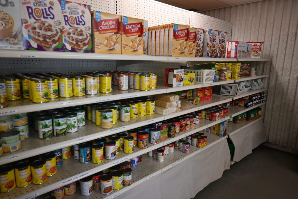 Labelled shelves inside the Barrhaven Food Cupboard, stocked with canned vegetables, beans and boxed cereal.
